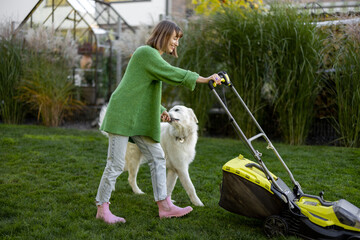 Woman plays with her dog at backyard while gardening