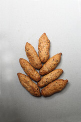 small French baguettes lying in the shape of ear of wheat on gray background flat lay