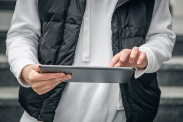 Close-up, a woman is using a tablet outside.