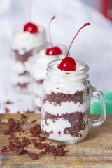 Dessert of chocolate cheese and cherry in jar with chocolate crumbs, selective focus on drink.