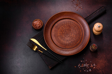 An empty brown ceramic plate on a dark concrete brown background