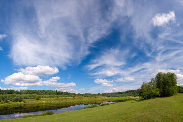 Rural river among the greenery of summer. Summer river in greenery outdoors. Rural river in summertime. Summer river landscape