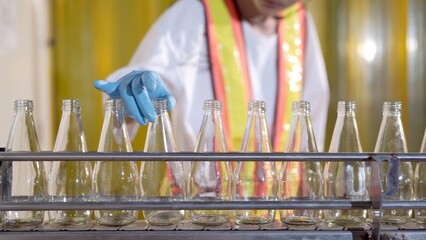 Senior professional quality control officer inspecting the manufacturing line and computer system in the beverage bottling factory. 