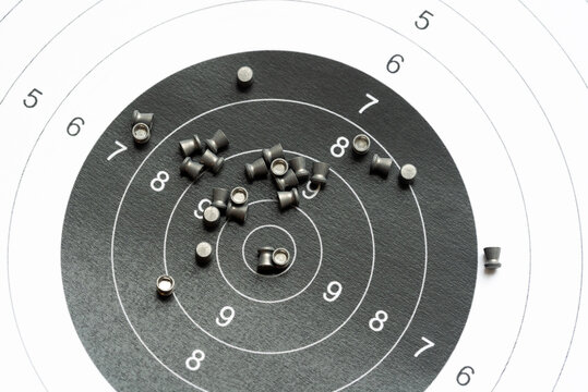 Simple shooting target and lots of metal pellets laying on top of it, object closeup, detail, nobody. Airguns, sport. Pellet ammo, air gun ammunition, range aim training, practice concept, no people