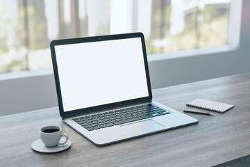Close up of empty white laptop on wooden desktop with coffee cup, notepad, pen, mock up place on screen, blurry office interior with window and city view background. 3D Rendering.