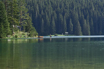 man sitting in the distance fishing on the lake in durmitor national park in montenegro