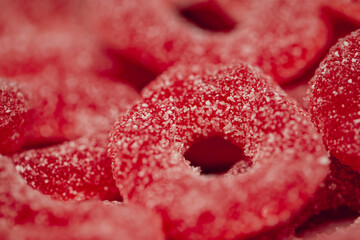 Red gummies jelly candies in sugar, background.