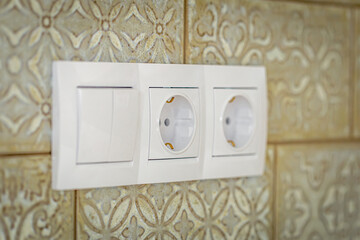 White plastic walk-through switches and sockets on a white wall.