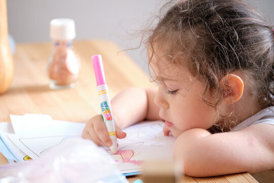Little girl playing iwth invisible ink and coloring book