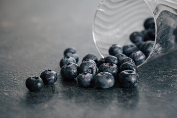 Macro photography, blueberries scattered on a dark surface.