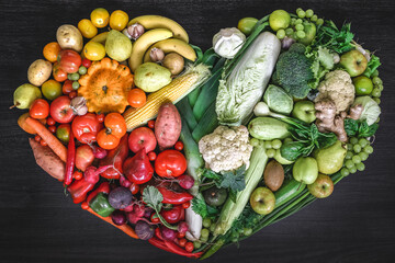 Heart made of fresh vegetables and fruit on wooden background.
