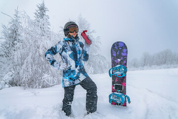 Snowboarder woman with thermos at winter snowy mountains