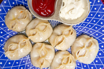 close-up manti and sauce on a blue plate top view