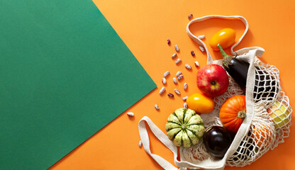 Eco bag with fresh organic vegetables and fruits on orange green background. Autumn harvest....