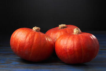 Three small bright orange pumpkins against the black background. Decoration for the Halloween holiday.
