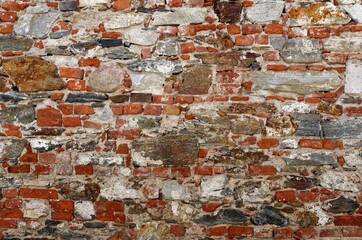 Texture of old wall built of red bricks and uneven stones