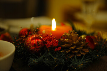 A red burning candle against a background of red berries, cones and fir branches. Postcard. Christmas concept