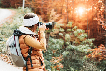 Young female photographer taking photos in the nature with her camera