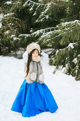portrait of beautiful cute little Asian girl in fur coat and fur hat standing in snowy forest in winter, winter holidays and having fun, Christmas vacation, selective focus in snowy weather