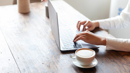 business woman drinking coffee and working on wooden table at home Using a laptop and computer to assess and analyze the economy to invest successfully in his own business, business ideas.