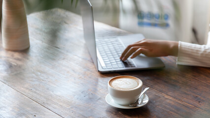 business woman drinking coffee and working on wooden table at home Using a laptop and computer to...