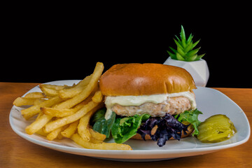 salmon burger top with tarter sauce and with fries