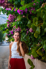 beautiful elegant woman in a white lace blouse and long red skirt walks through the Mediterranean town of orebić on the peljesac peninsula; holiday in croatia