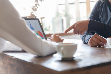 Two businessmen talking in a board room about joint business and summarize the company's profits with a graph showing successful performance. A colleague reviewed the results of the quarterly report.