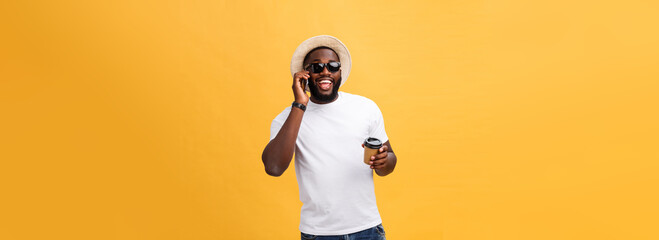 Handsome African American with mobile phone and take away coffee cup. Isolated over yellow gold...