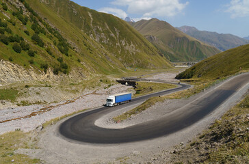 A white truck drives along a winding mountain road.