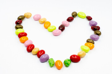 Heart made of colorful candy dragees. Dragee candies isolated on white background. Heart figure made of candy.

