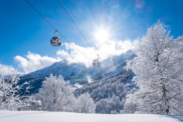 Winter Mountain landscape at the Rosa Khutor ski resort in Sochi, Russia. Trees in hoarfrost against a beautiful morning sky in a frosty morning. Snow cannons sprinkle snow on the slopes