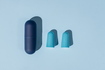 Blue ear plugs made of foam for comfortable sleep on blue background. Insomnia concept, flat lay