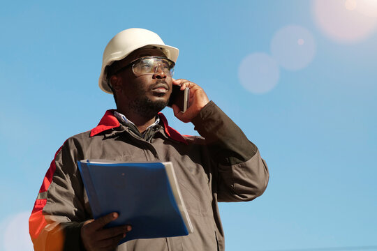 Busy african american works manager with work papers talks on smartphone