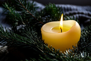 A small burning candle among the branches of a spruce