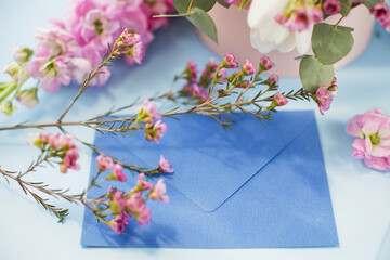 Blue envelope and pink gift box with bouquet on a blue background