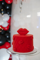 Red fresh delicious birthday cake on table on white background with lights and color balloons. Kiss as decor on a cake. Sweet for your holiday. Concept for Valentine's Day. Red lips.