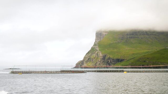 Crusing on a boat next to a fish farm in the Atlantic ocean, Faroe Islands. Hills hidden in the fog. High quality 4k footage.