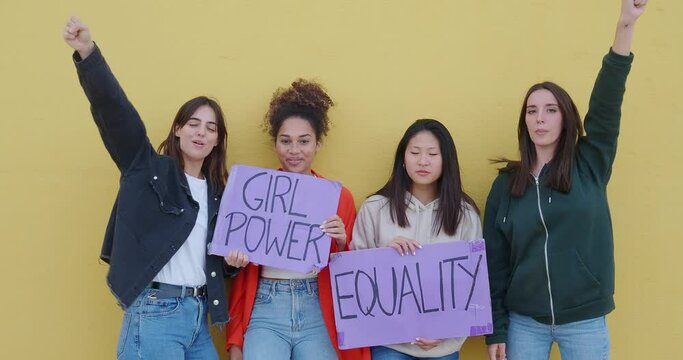 Group of multiethnic young women with feminist signs on a yellow background. Feminism, empowered women