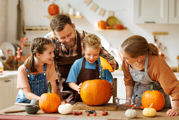 Happy family mother, father and kids  to remove pulp from from pumpkin while carving jack o lantern...