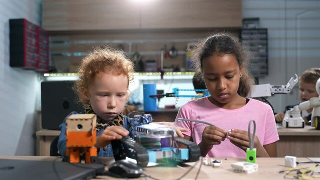 Brilliant diverse elementary school girls working on robotics in class. Group of multiethnic children assembling their first robots and electric toys. STEM education concept.