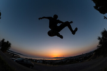 Young male jump with high energy with a low angle shot and colorful sunset sky at background