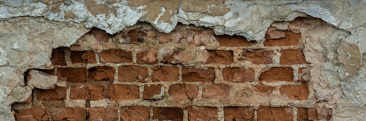 old brick wall with peeling cement plaster. widescreen horizontal side view