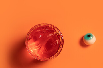 Eyeball and orange gel in a jar on orange background