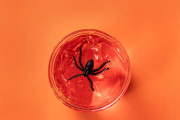 Black spider in orange gel jar on orange background