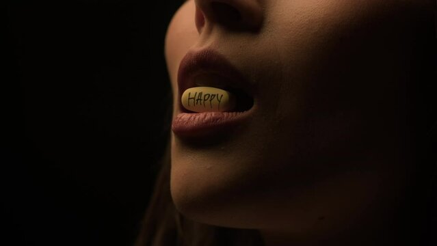 Hard time. A woman swallows a pill of happiness in the dark.