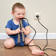 Child boy chewing on the electric wire of a curling iron. Toddler baby plays with hot curling tongs...