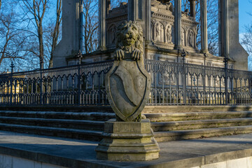 concrete lion statue with shield on pedestal close up photo in sunny weather statue is old with...