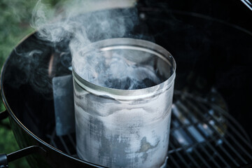 Kindling for coal and smoke on a blurred background of a black round metal grill. Close-up. Selective focus.