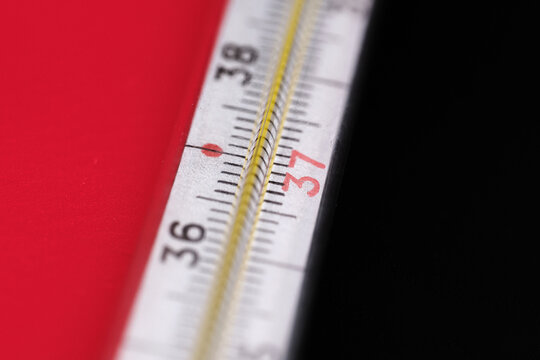 Fragment of an old mercury thermometer. Close-up. Red-black background. Selective focus.